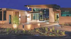 Bold roof forms and timeless materials heighten the impact of The New American Home 2024’s all-glass entry, which provides a glimpse of the interior and dramatic views of the Las Vegas Valley beyond. | Photo: Levi Ellyson/501 studios