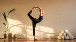 woman doing yoga at sunset time in a studio By merla - Adobe Stock