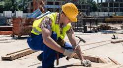 Construction worker on jobsite hammering nail into board