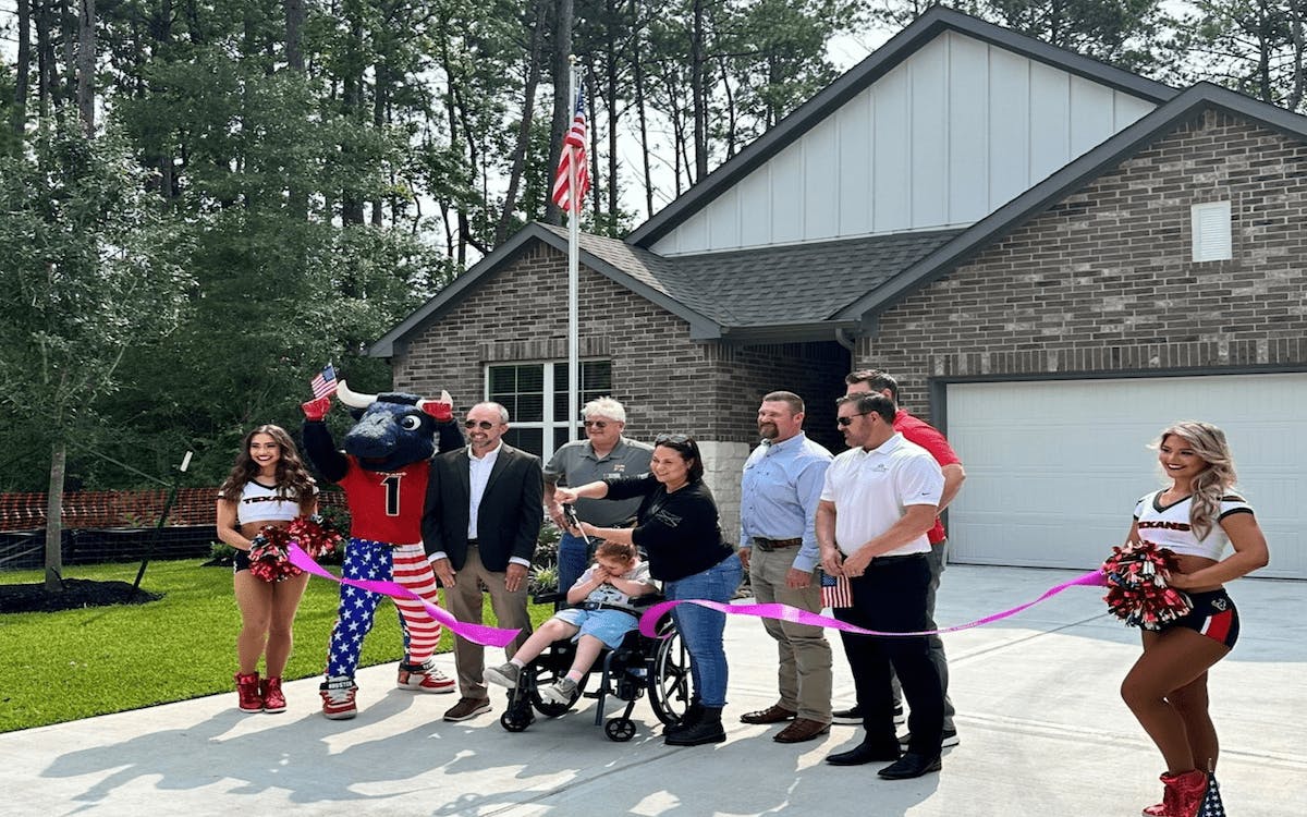 The Ellenbeck family, along with the development team and the Houston Texans, hold a welcoming ceremony in front of their newly built home.