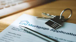 A mortgage application sits on a desk with a pen and a house key on top of it