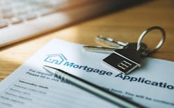 A mortgage application sits on a desk with a pen and a house key on top of it A mortgage application sits on a desk with a pen and a house key on top of it