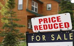 A 'For Sale' sign with a 'Price Reduced' sign added above it sit in front of an older home A 'For Sale' sign with a 'Price Reduced' sign added above it sit in front of an older home