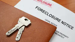 A foreclosure notice with keys on top sit on a table