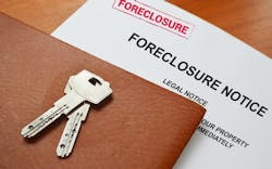 A foreclosure notice with keys on top sit on a table A foreclosure notice with keys on top sit on a table