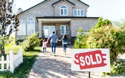 A family holds hands, running toward a single-family home with a 'Sold' sign in the front yard A family holds hands, running toward a single-family home with a 'Sold' sign in the front yard