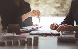 A selling agent hands over the keys to a buyer as they fill out paperwork A selling agent hands over the keys to a buyer as they fill out paperwork