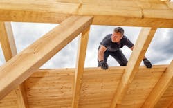 A builder works on the roof of a building A builder works on the roof of a building