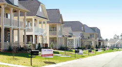 Pictured is a row of homes, and one home has a 'for sale' sign in the front yard with a secondary sign reading 'reduced.'