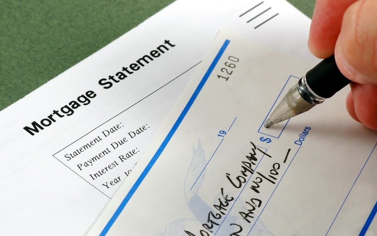 A closeup image of a hand writing out a check to a mortgage company