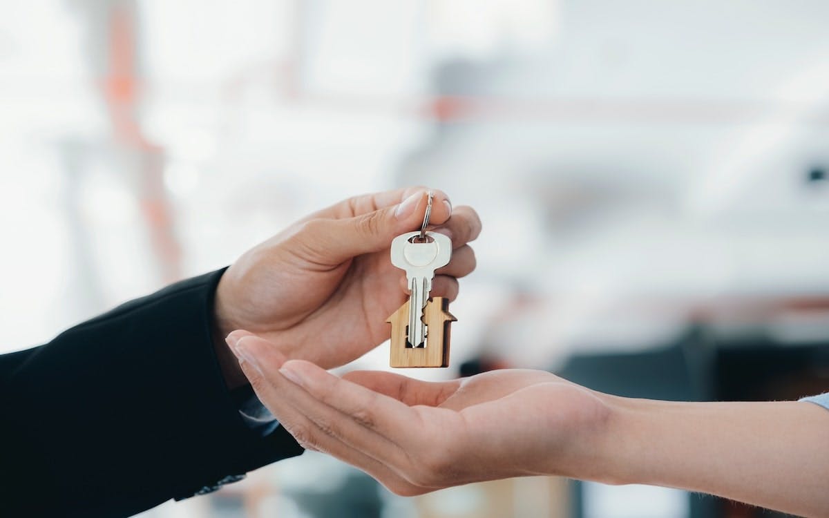 A real estate agent hands a key over to a homebuyer