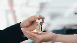 A real estate agent hands a key over to a homebuyer