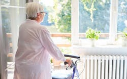 An elderly woman stares out the window of her home An elderly woman stares out the window of her home