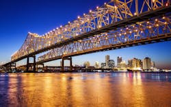 A bridge in New Orleans is illuminated at night with the city skyline behind it A bridge in New Orleans is illuminated at night with the city skyline behind it