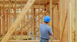 A home builder looks over at framing on new-construction home