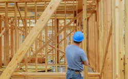 A home builder looks over at framing on new-construction home