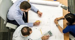 Builder and trades at table reviewing house plans Builder and trades at table reviewing house plans