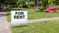 A 'For Rent' sign posted in a front yard