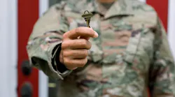 A man in a U.S. Army uniform holds up a key to a new home