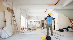A man in a yellow hard hat looks over home renovation work