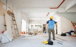 A man in a yellow hard hat looks over home renovation work A man in a yellow hard hat looks over home renovation work