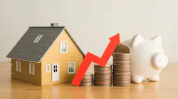 A model home and piggy bank sit next to three stacks of coins placed in ascending order from left to right, indicating financial growth