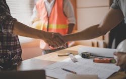 A worker and a homeowner shake hands, negotiating a job. A worker and a homeowner shake hands, negotiating a job.
