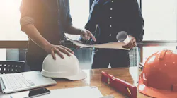 Two construction workers go over plans