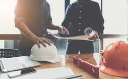 Two construction workers go over plans Two construction workers go over plans