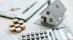 Shown is a table with a mortgage agreement, model home, calculator, and several stacks of coins.