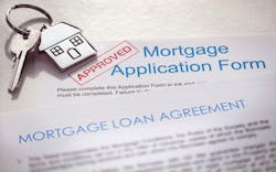 A mortgage loan application with a stamp of approval and a set of house keys on top of it A mortgage loan application with a stamp of approval and a set of house keys on top of it