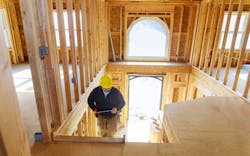 A contractor walks up the stairs in a partially constructed home A contractor walks up the stairs in a partially constructed home