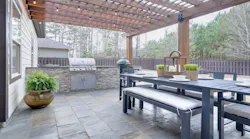 A covered patio with grill and dining area