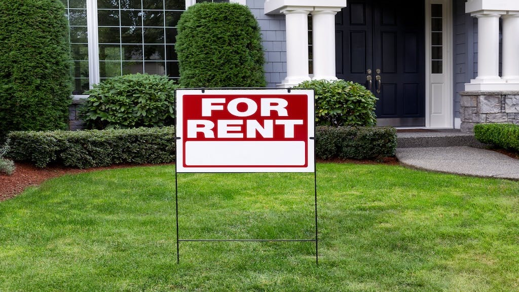 A blue single-family home with red 'For Rent' sign in the front yard
