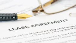 A close-up of a lease agreement with a pair of glasses and a pen sitting on top of them. A close-up of a lease agreement with a pair of glasses and a pen sitting on top of them.