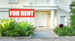 A single-family home sits in the background. In the foreground is a red sign reading 'For Rent.'