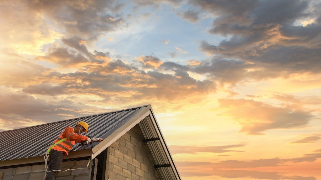 Builder works on roof of a home during sunrise