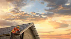 Builder works on roof of a home during sunrise