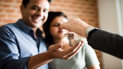 A smiling couple takes house keys from a real estate agent after purchasing their home. A smiling couple takes house keys from a real estate agent after purchasing their home.