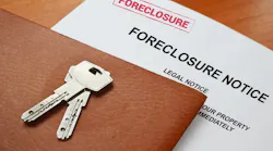 Closeup of a foreclosure notice with a leather folder and house key sitting on top