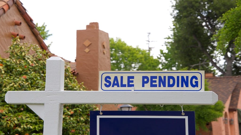 Blue sign in front of a home reading 'sale pending'