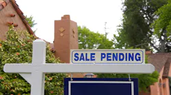 Blue sign in front of a home reading 'sale pending'