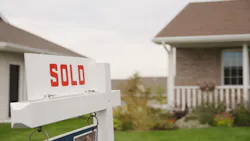A white sign with the word 'sold' on it sits in front of a single-family home