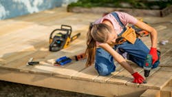 A woman carpenter works on a home decking project. A woman carpenter works on a home decking project.