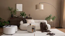 An organic modern living room, with warm brown walls, wooden dresser, large floor lamp, and white couch