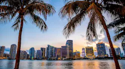 The Miami skyline at sunset is framed between two palm trees