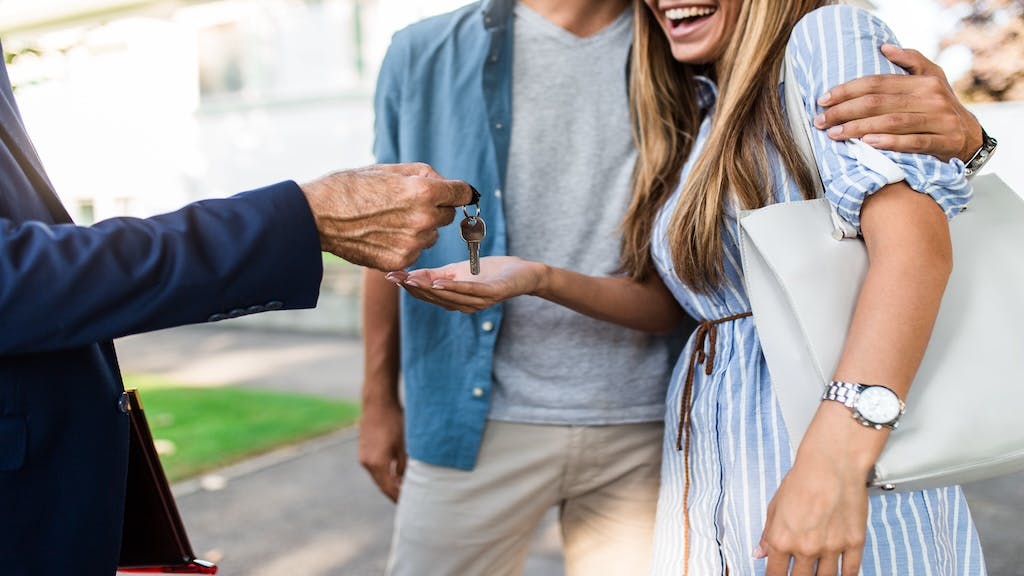 A happy young couple takes house keys from a real estate agent