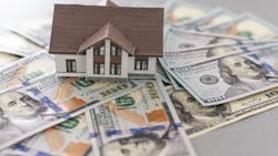 A small model home sits on a pile of $100 bills. A small model home sits on a pile of $100 bills.