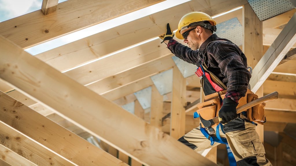 A contractor works on the roof of a house.