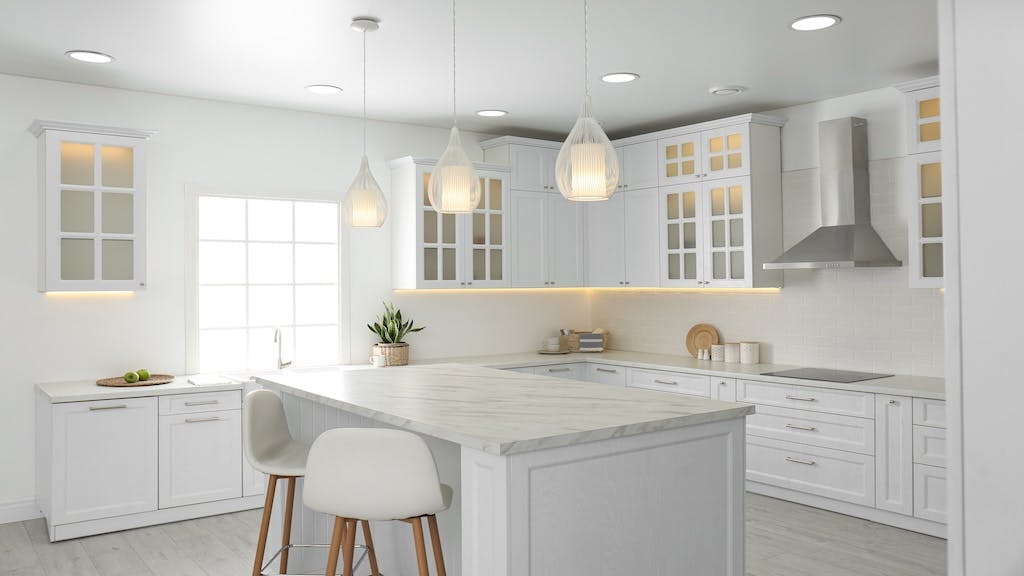 A fully white kitchen with an island in the center.